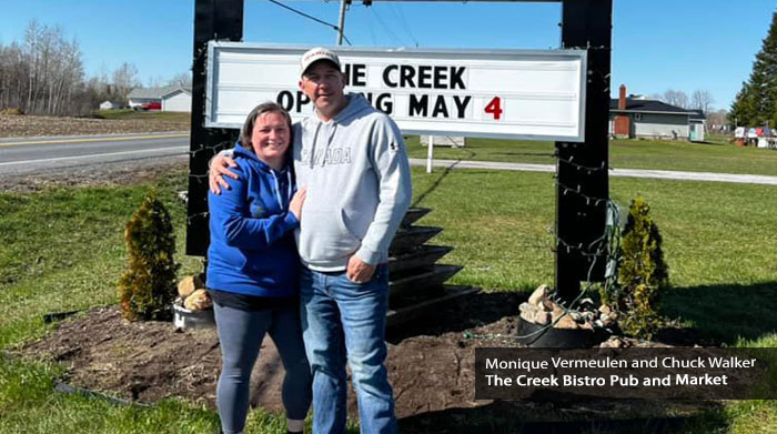 Monique and Chuck from the Creek Bistro Pub and Market in front of the sign.